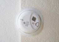 White smoke detector mounted on a white wall